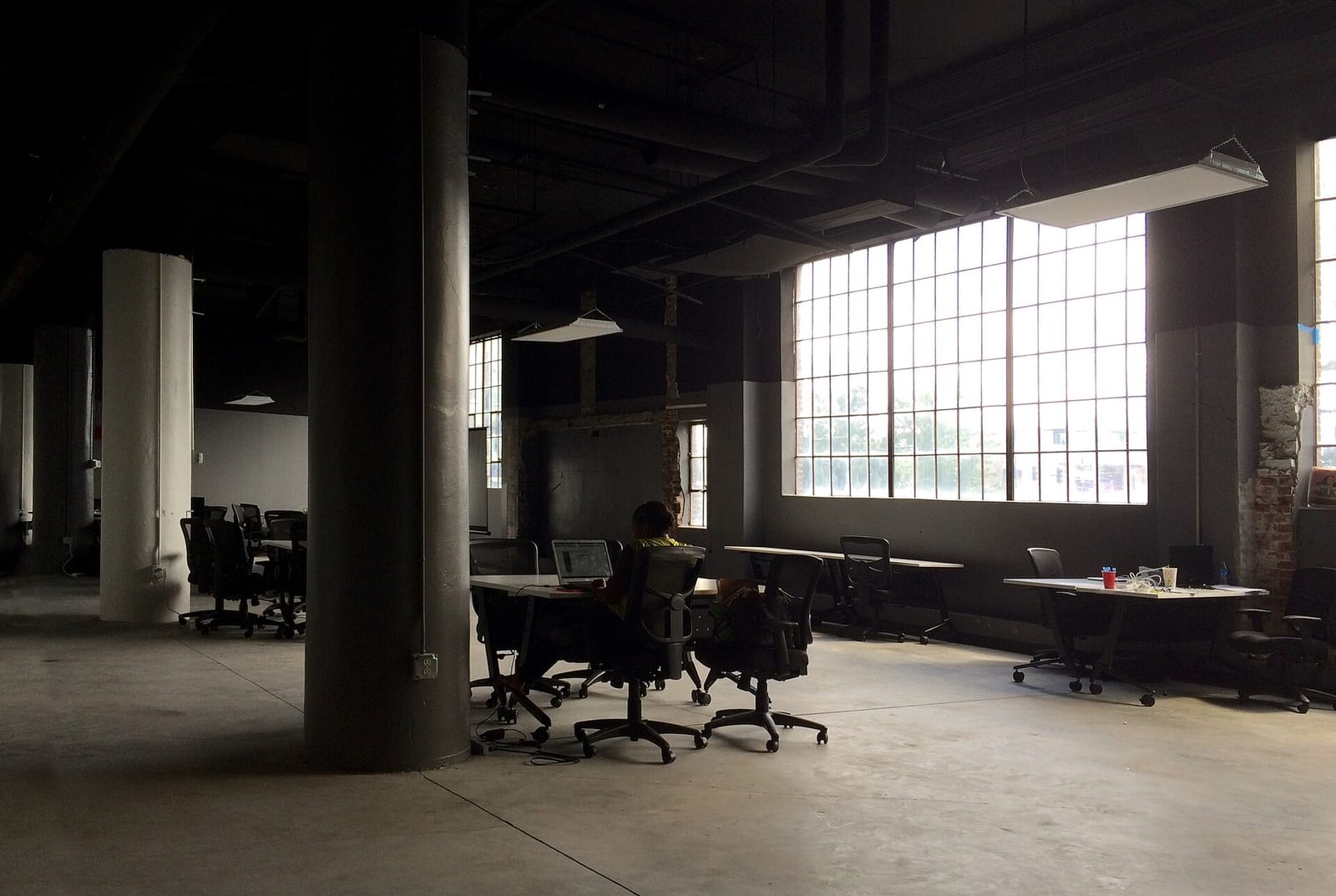 A single worker at a desk in a large open-plan office