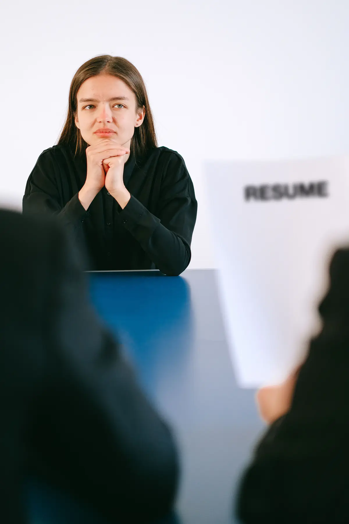 A woman at a table during a job interview with her resume in the foreground