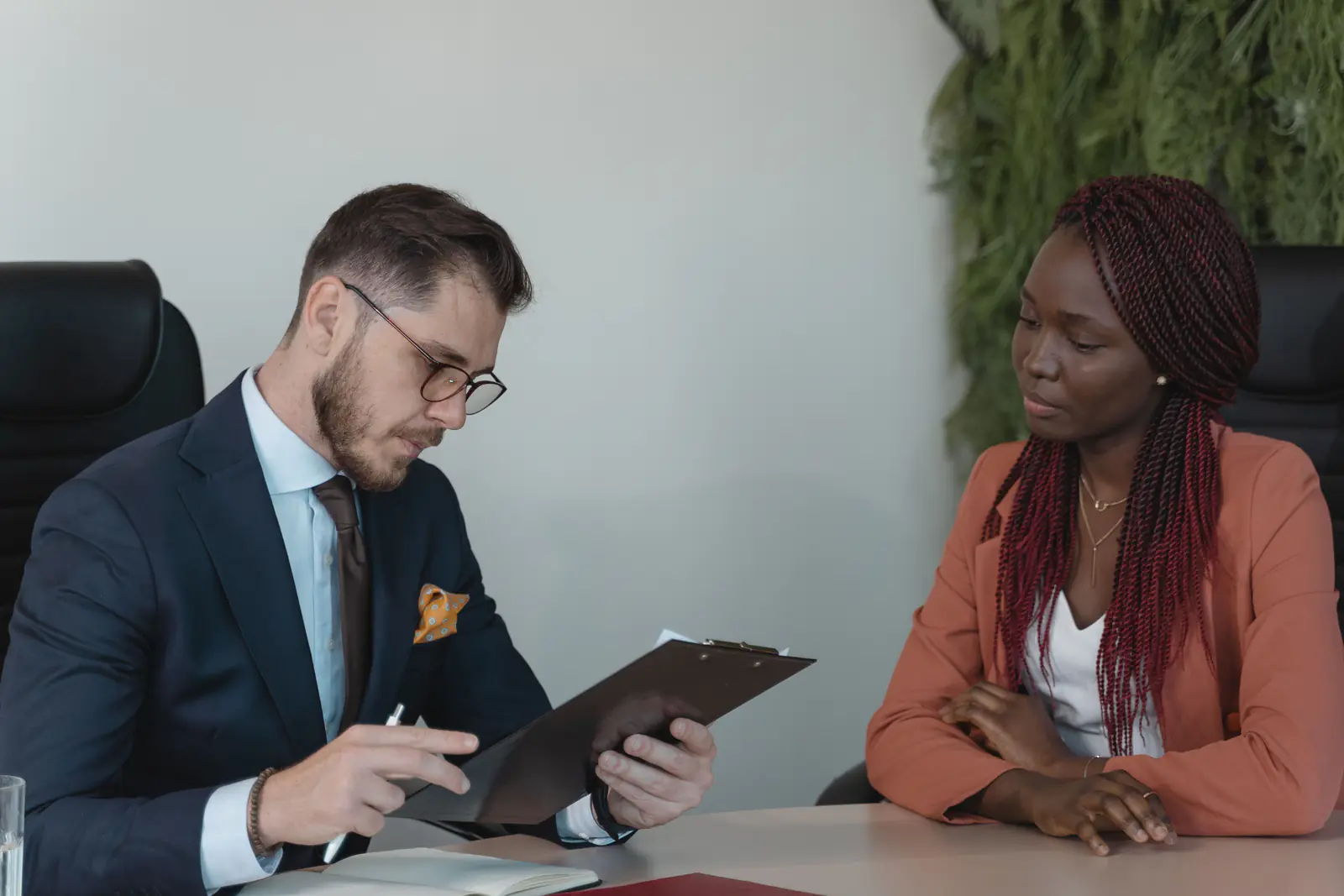 A man and a woman talking during a job interview in a modern office, with a resume on the desk