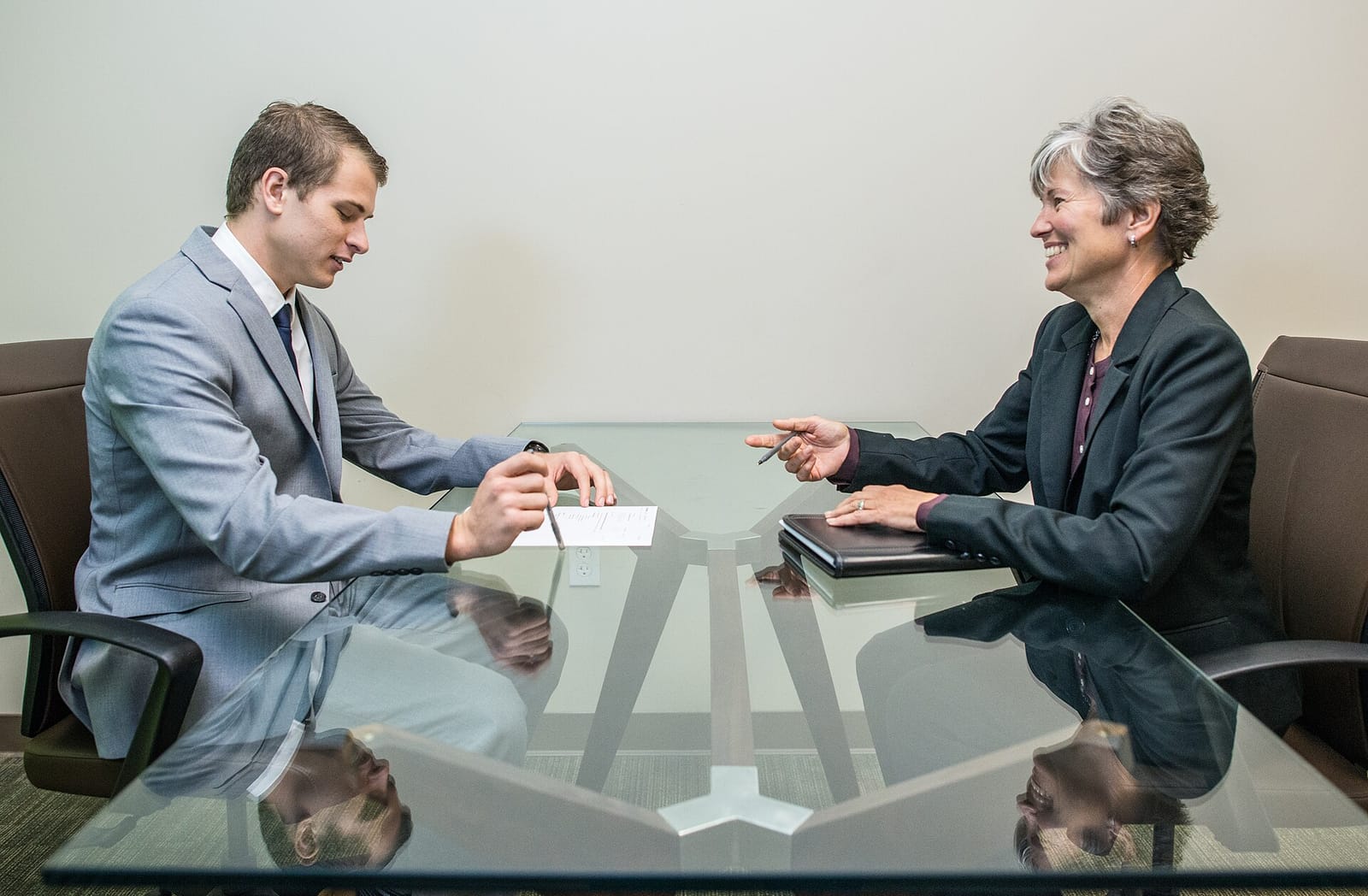 A job candidate and an interviewer talking across a glass table