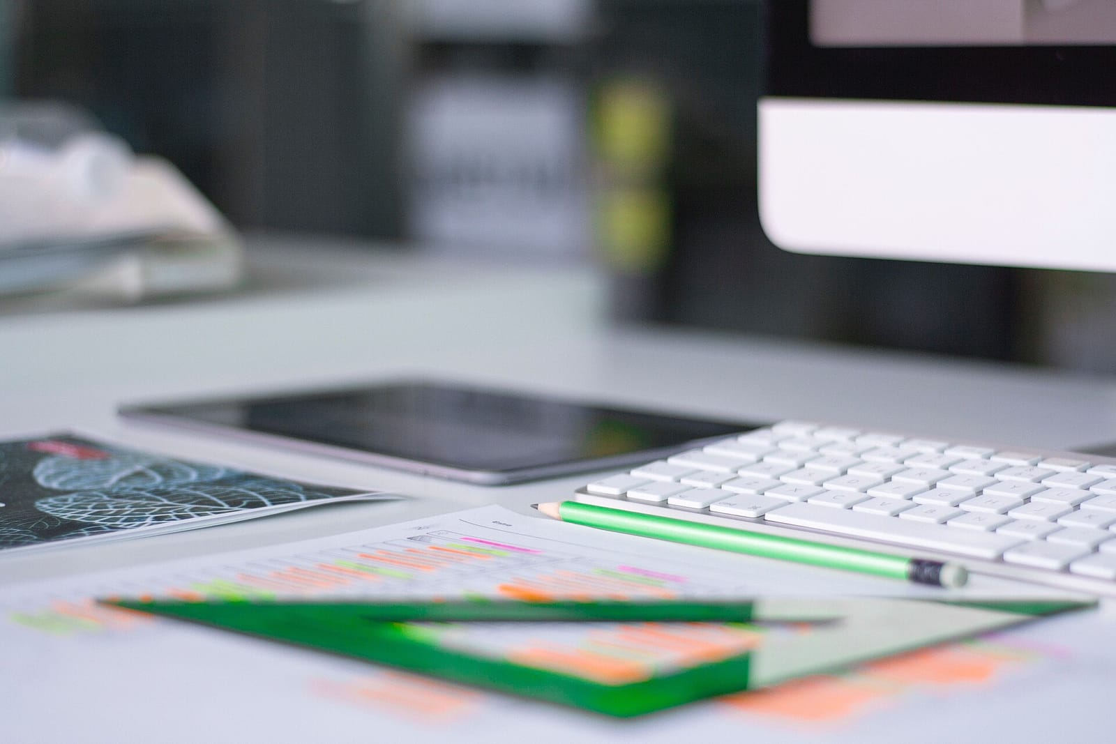 An office desk with a keyboard, tablet and printed charts