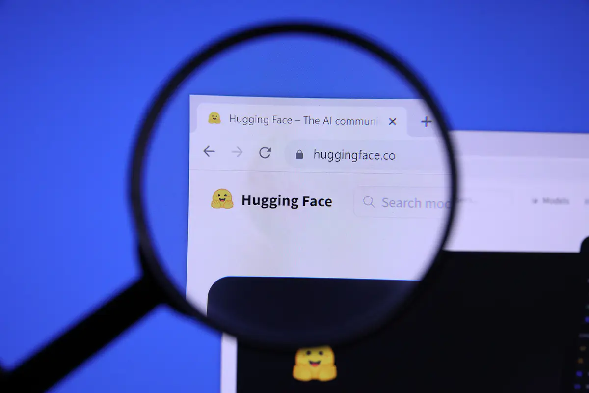 The Hugging Face website homepage with its logo magnified under a magnifying glass