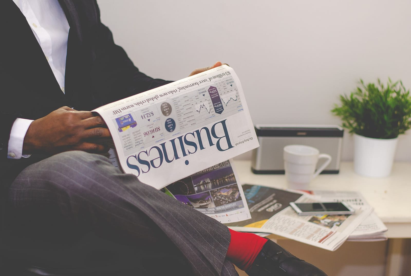 A person in a suit reading the business section of a newspaper at a desk
