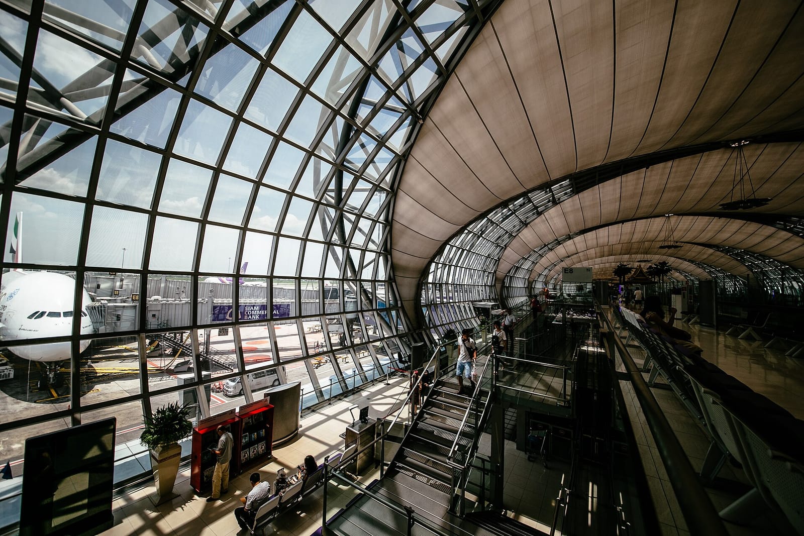 Interior of an airport terminal with a curved glass and steel roof