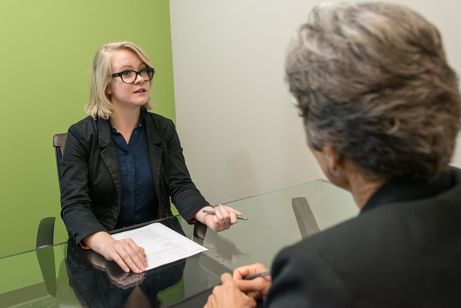 A woman sitting across a table from an interviewer during a job interview