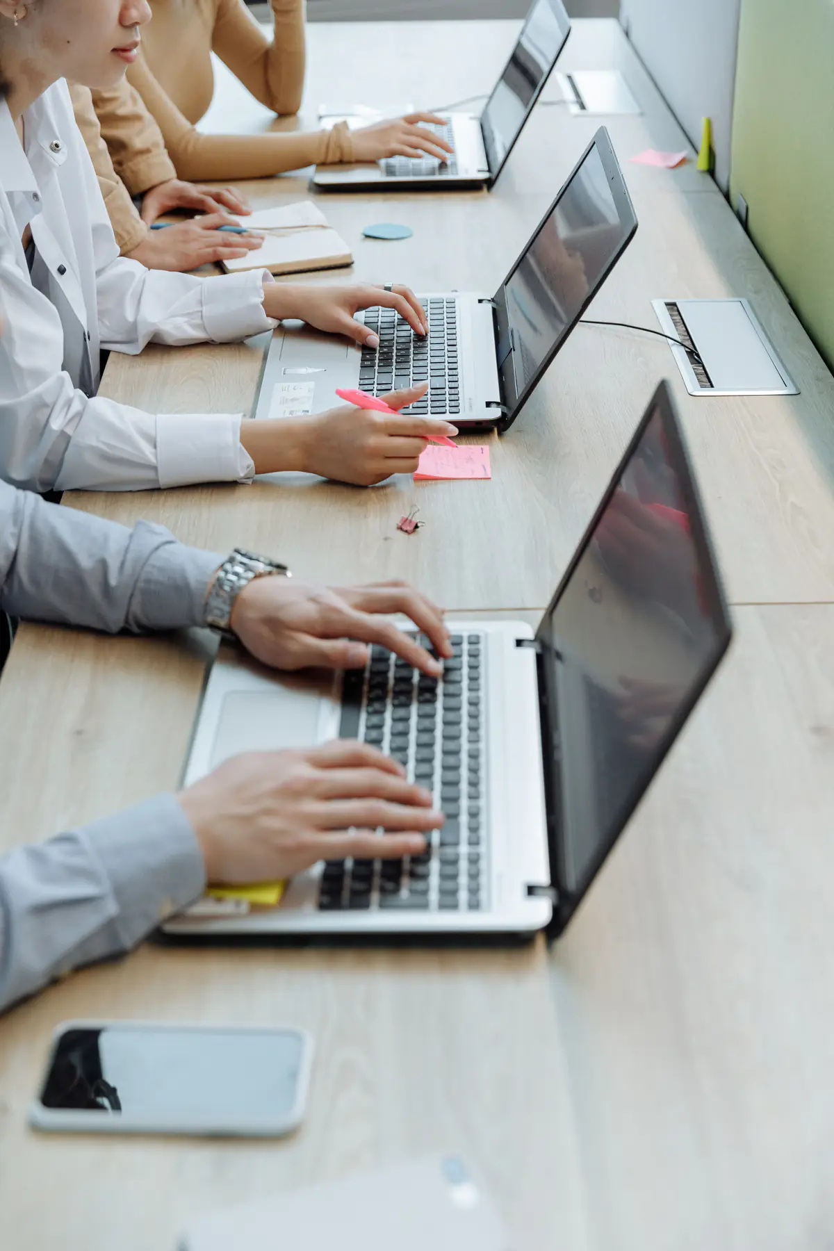 Office workers typing on laptops at a shared desk