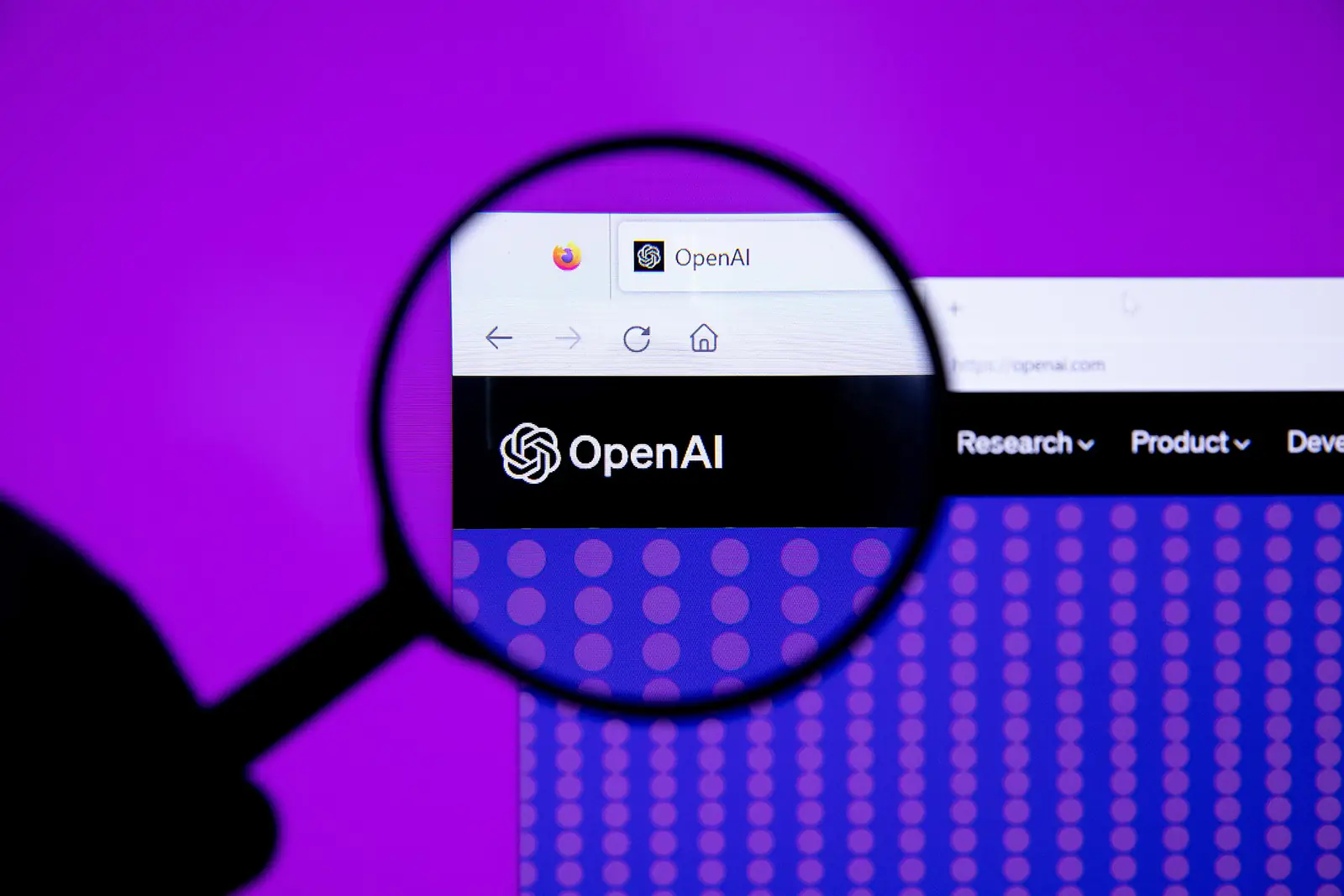 The OpenAI logo displayed on a screen and viewed through a magnifying glass